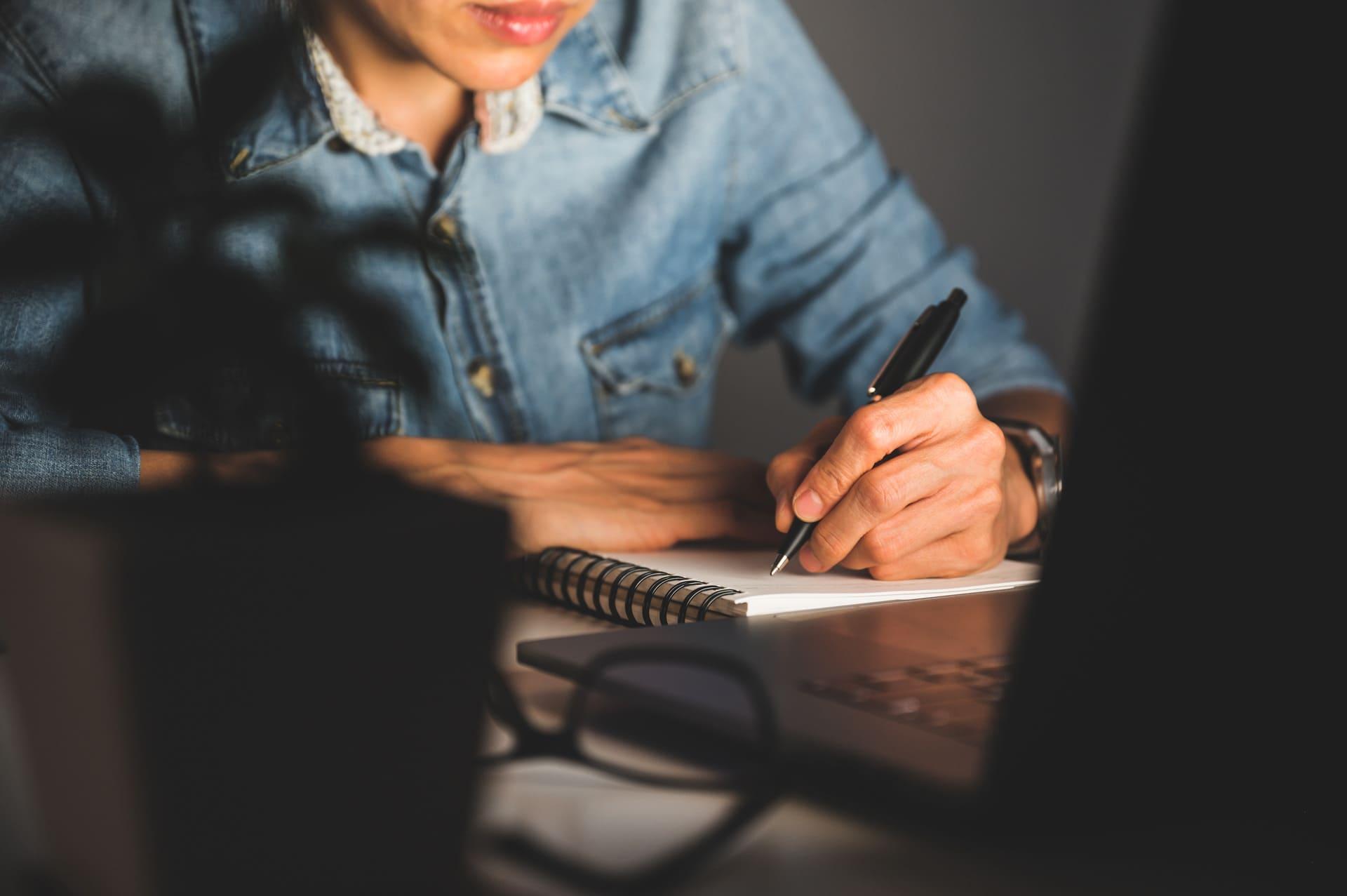 Persona en un escritorio tomando notas en una libreta