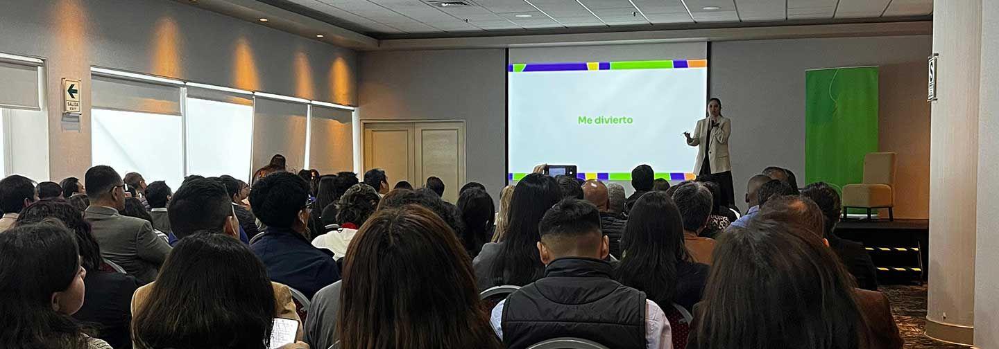 Asistentes sentados en un aula, concentrados en una presentación que se desarrolla en la pantalla.